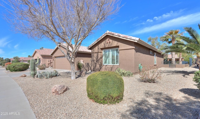 view of front of house featuring a garage, fence, concrete driveway, a tiled roof, and stucco siding