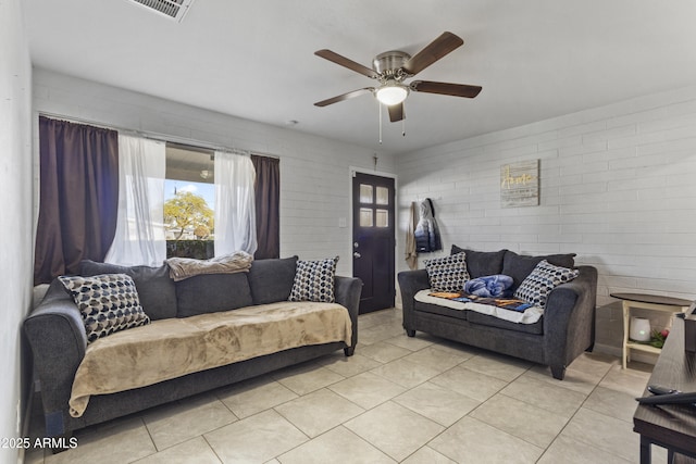 tiled living room featuring ceiling fan and brick wall