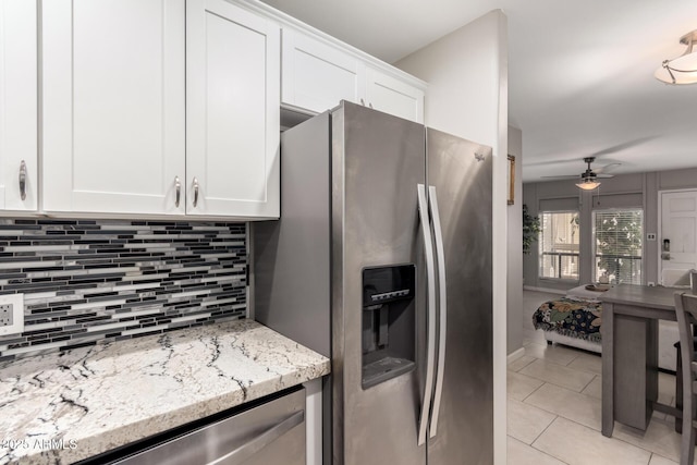 kitchen with light tile patterned flooring, stainless steel appliances, light stone countertops, and white cabinets