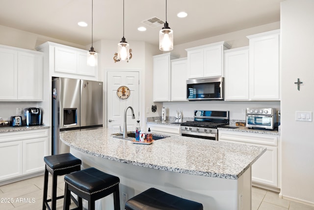 3655 N Astoria Dr, Florence, AZ 85132 - kitchen featuring appliances with stainless steel finishes, a sink, light tile patterned floors, a kitchen breakfast bar, and an island with sink