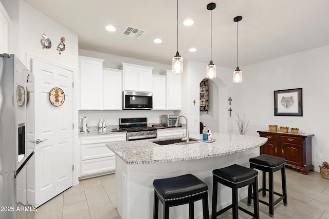 3655 N Astoria Dr, Florence, AZ 85132 - kitchen featuring stainless steel appliances, a sink, a breakfast bar, an island with sink, and white cabinets