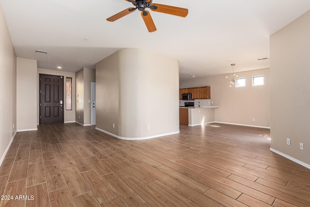 unfurnished living room with hardwood / wood-style flooring and ceiling fan with notable chandelier