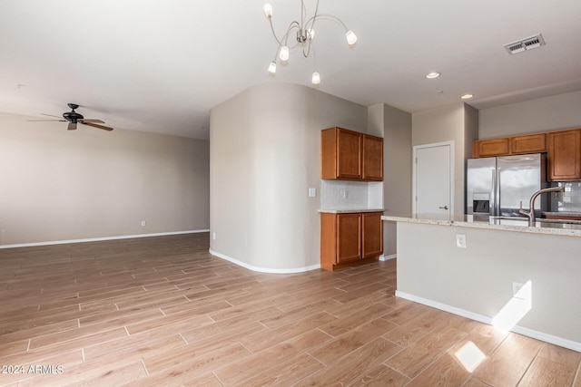 kitchen with light hardwood / wood-style floors, stainless steel fridge, light stone countertops, and pendant lighting