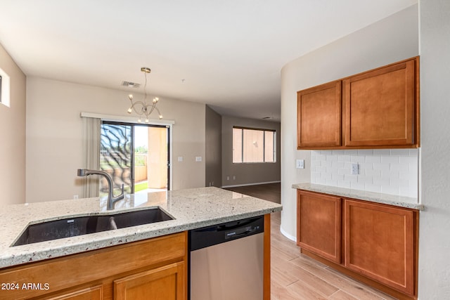 kitchen featuring light stone countertops, dishwasher, light wood-type flooring, and hanging light fixtures