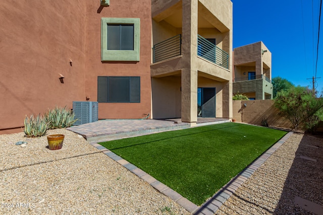 rear view of property with a balcony, a patio area, and a lawn