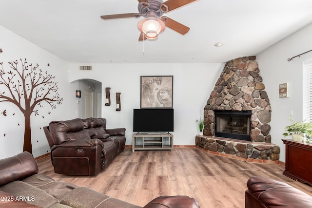 1730 W Adamanda Ct, Phoenix, AZ 85086 - living room featuring arched walkways, a ceiling fan, wood finished floors, and a stone fireplace