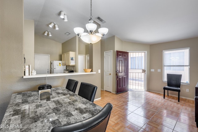 dining room with light parquet flooring, vaulted ceiling, and a chandelier