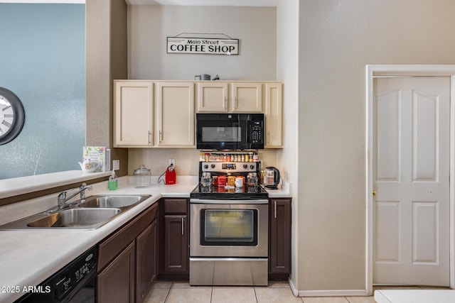 kitchen with sink, light tile patterned floors, dark brown cabinets, black appliances, and cream cabinetry