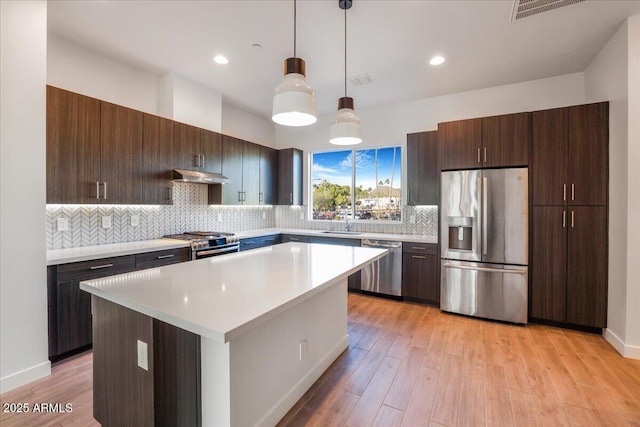 1717 E Morten Ave Unit 2, Phoenix, AZ 85020 - kitchen featuring dark brown cabinets, stainless steel appliances, decorative light fixtures, light hardwood / wood-style floors, and a center island