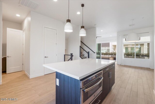 1717 E Morten Ave Unit 2, Phoenix, AZ 85020 - kitchen featuring a kitchen island, oven, hanging light fixtures, and light hardwood / wood-style floors