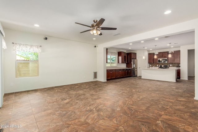 unfurnished living room featuring plenty of natural light and ceiling fan