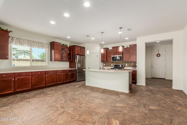 kitchen featuring appliances with stainless steel finishes, hanging light fixtures, sink, decorative backsplash, and an island with sink