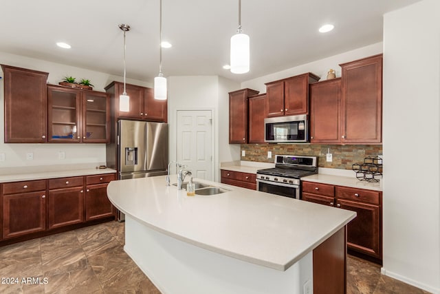 kitchen featuring a center island with sink, sink, appliances with stainless steel finishes, pendant lighting, and decorative backsplash