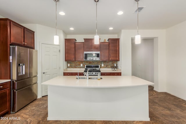 kitchen with decorative light fixtures, a center island with sink, and stainless steel appliances