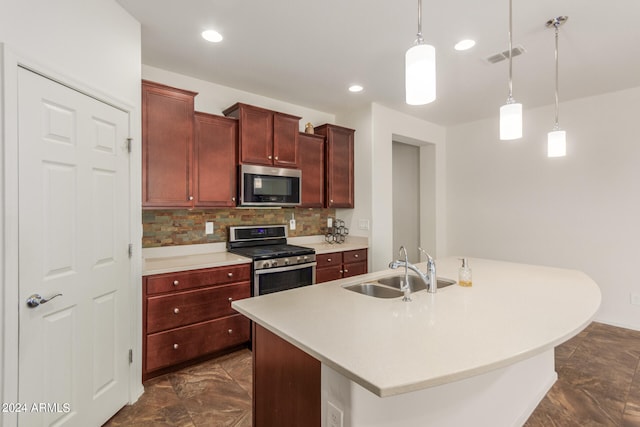 kitchen featuring sink, appliances with stainless steel finishes, a kitchen island with sink, pendant lighting, and decorative backsplash