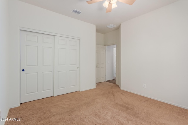 unfurnished bedroom with light carpet, ceiling fan, and a closet