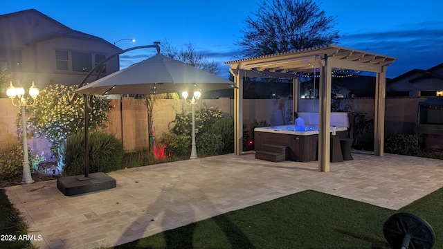 patio terrace at dusk with a hot tub and a pergola