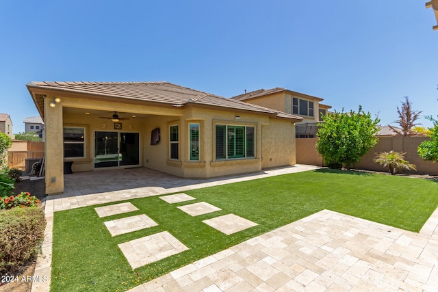 rear view of property with ceiling fan, a patio, and a yard