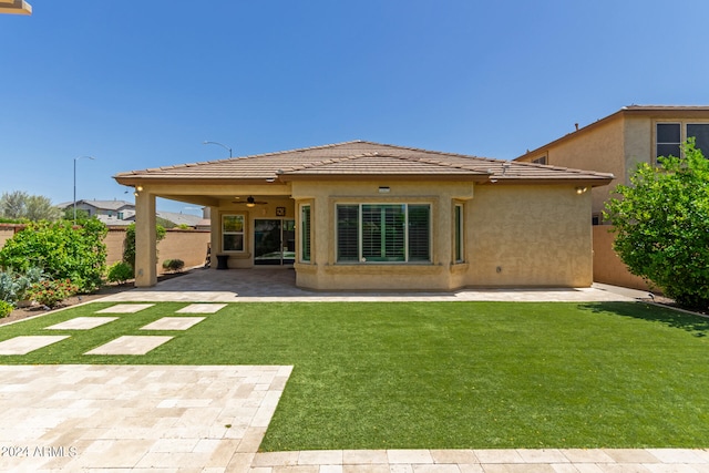 rear view of house with ceiling fan, a yard, and a patio