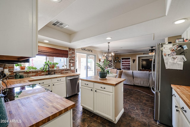 kitchen with wooden counters, appliances with stainless steel finishes, sink, and a kitchen island