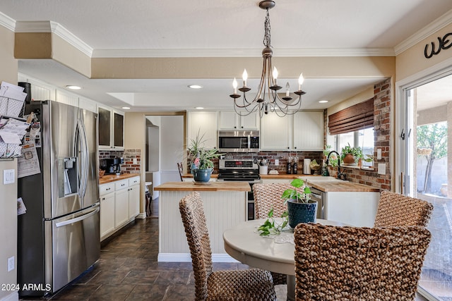 kitchen with wooden counters, pendant lighting, decorative backsplash, white cabinetry, and appliances with stainless steel finishes