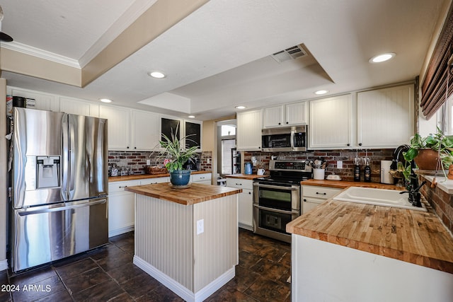 kitchen with butcher block counters, appliances with stainless steel finishes, and white cabinets