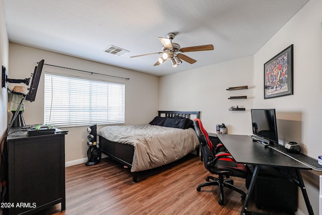 bedroom with a textured ceiling, hardwood / wood-style floors, and ceiling fan