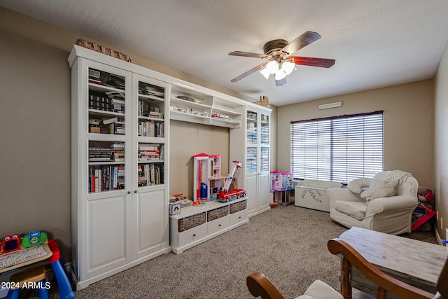 rec room with a textured ceiling, carpet flooring, and ceiling fan