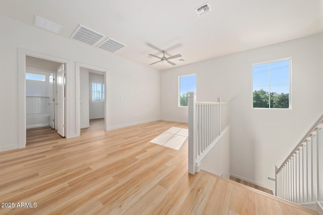 spare room featuring light wood-type flooring, ceiling fan, and a healthy amount of sunlight