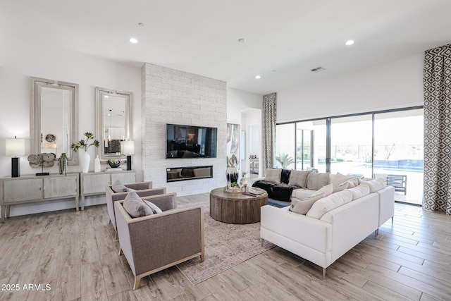 living room featuring light wood-type flooring and a stone fireplace