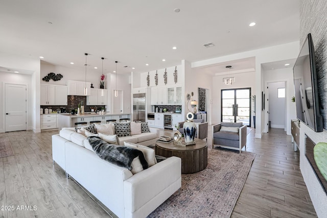 living room featuring light wood-type flooring, beverage cooler, and french doors