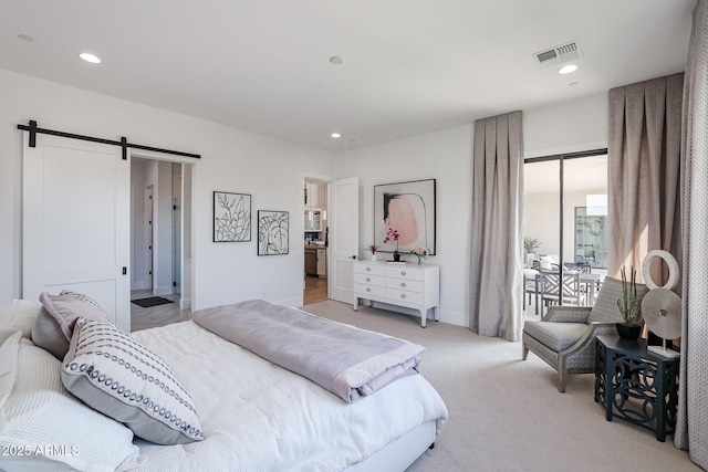 bedroom featuring a barn door and light colored carpet