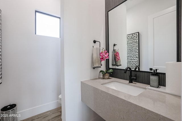 bathroom with toilet, vanity, and wood-type flooring