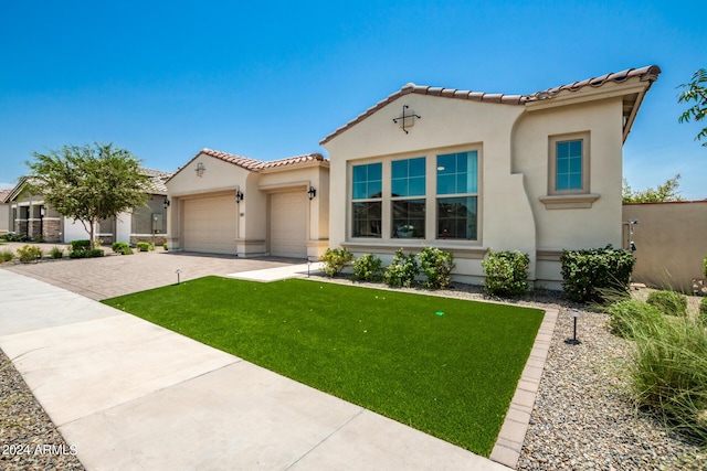 mediterranean / spanish home featuring a front yard and a garage