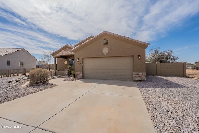 view of front of home featuring stucco siding, stone siding, concrete driveway, and fence