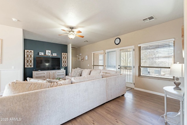 living area featuring ceiling fan, visible vents, baseboards, and wood finished floors