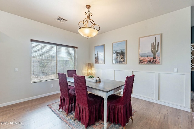 dining room featuring wood finished floors, visible vents, and baseboards