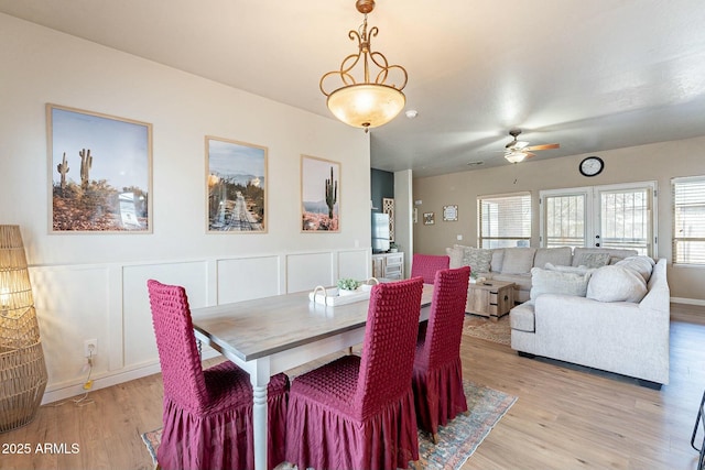 dining space featuring a decorative wall, light wood finished floors, and ceiling fan