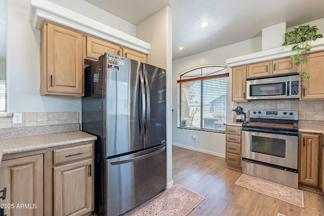 kitchen featuring light wood-style floors, backsplash, appliances with stainless steel finishes, and light brown cabinets