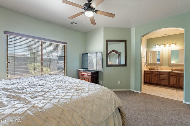 bedroom featuring light tile patterned floors, visible vents, arched walkways, a sink, and light colored carpet