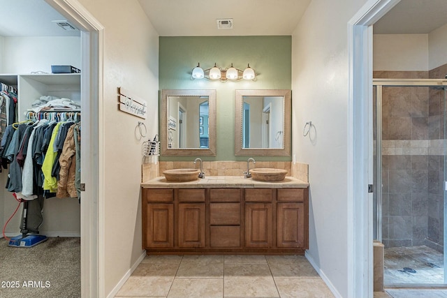 full bath with a sink, visible vents, a stall shower, and double vanity