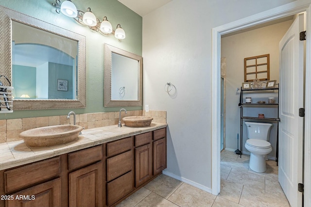 full bathroom with double vanity, baseboards, tile patterned floors, and a sink