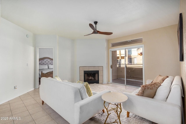 tiled living room with ceiling fan and a tile fireplace