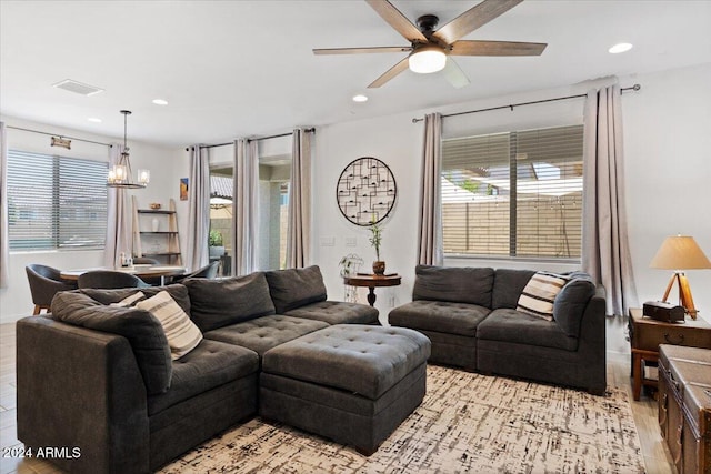 living room featuring ceiling fan with notable chandelier and light hardwood / wood-style floors