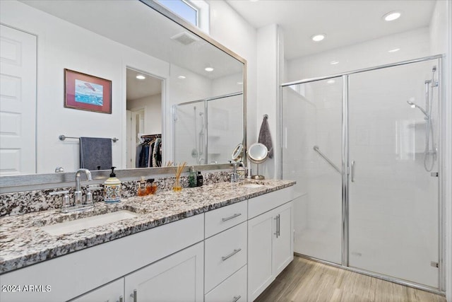 bathroom with hardwood / wood-style floors, vanity, and a shower with door