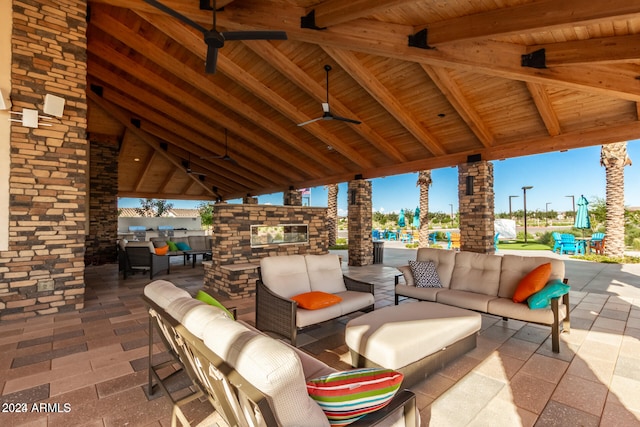 view of patio with ceiling fan, a gazebo, and an outdoor living space with a fireplace