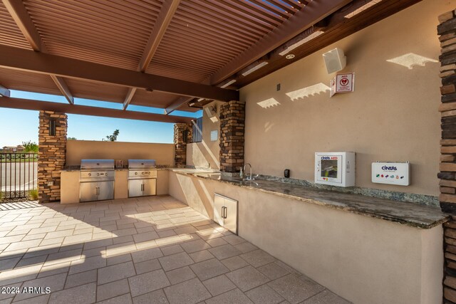 view of patio featuring an outdoor kitchen, area for grilling, and sink