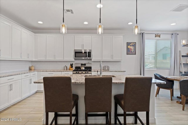 kitchen featuring white cabinets, stainless steel appliances, and light stone countertops