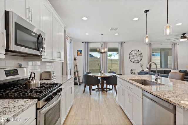 kitchen with stainless steel appliances, hanging light fixtures, white cabinets, and sink