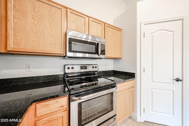 kitchen featuring stainless steel appliances, dark stone countertops, and light brown cabinets